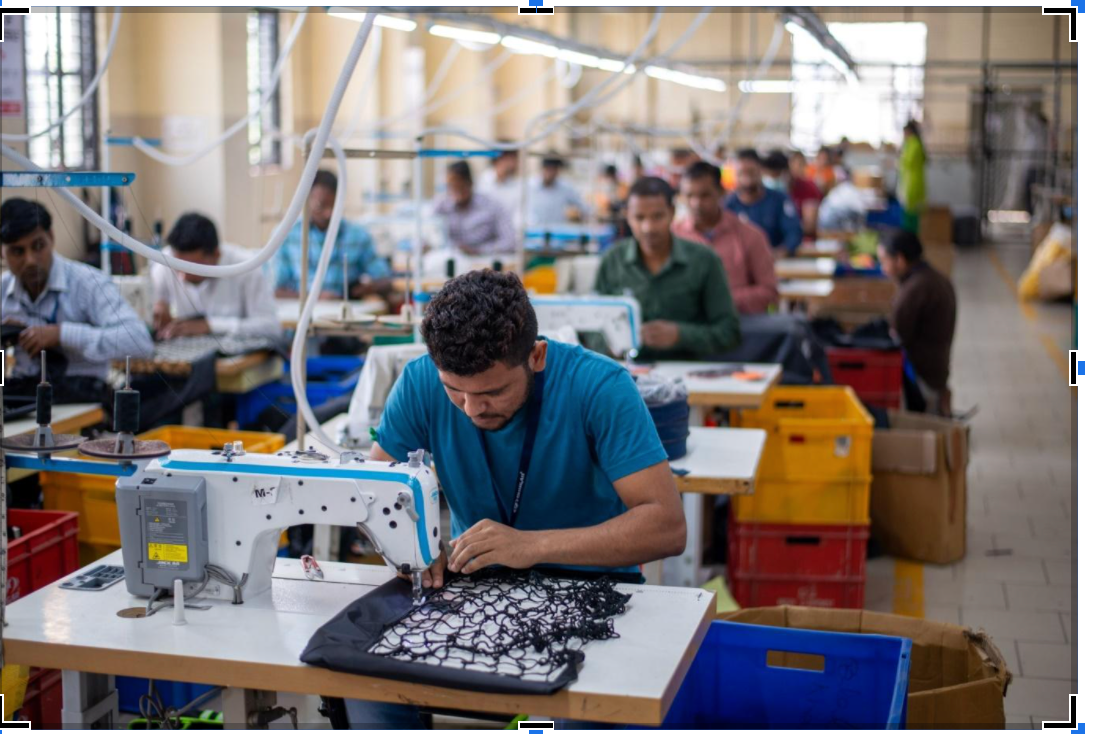 Indian garment factory workers sewing textiles in organized production line